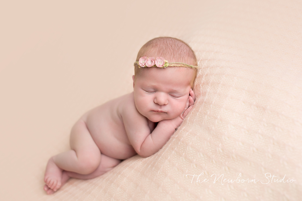 newborn baby girl on peach background