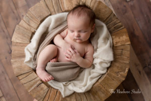 baby boy curled up in timber bowl