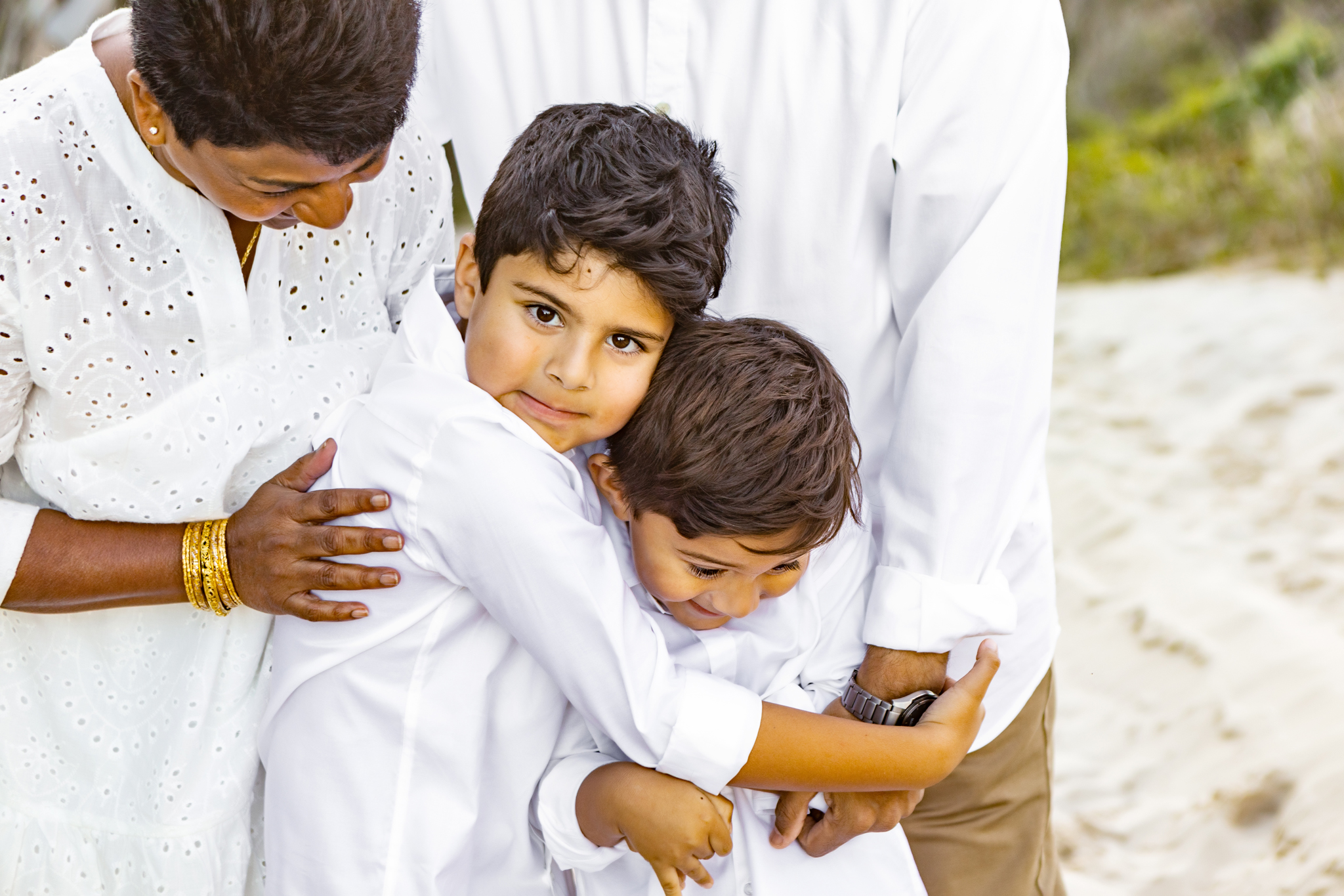 Two grandkids being hugged by their grandparents at the beach