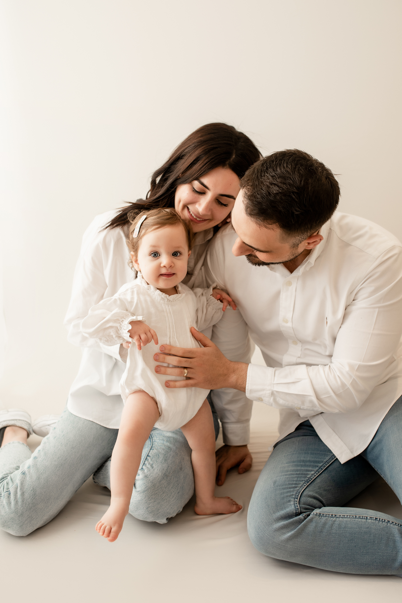 family of 3 cuddling baby girl in photo studio