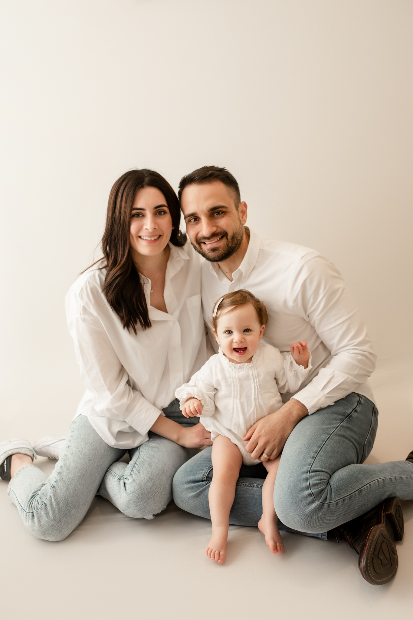 family of 3 cuddling smiling at camera in photo studio