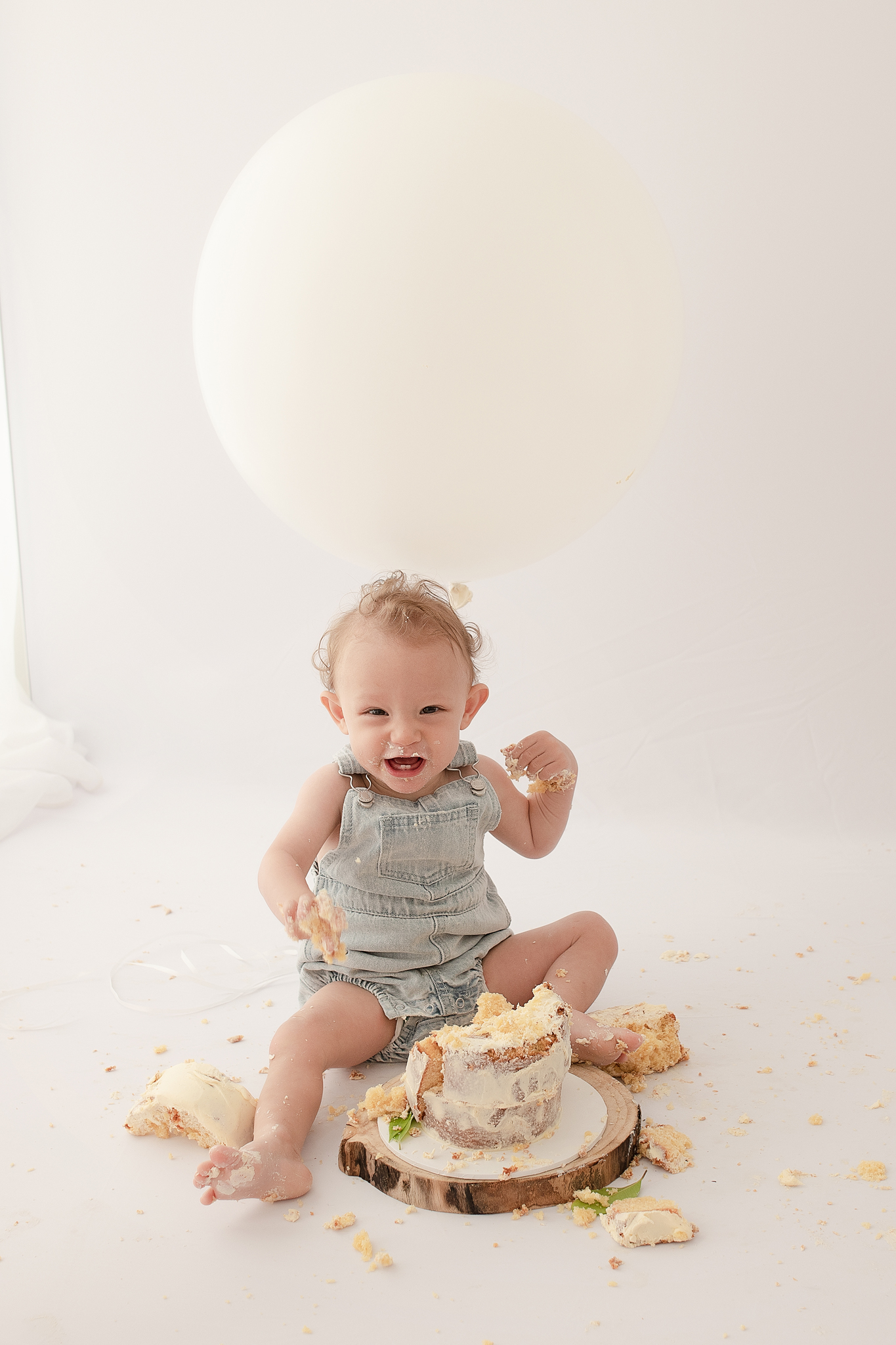 very happy excited one year old boy smashing cake in photo studio