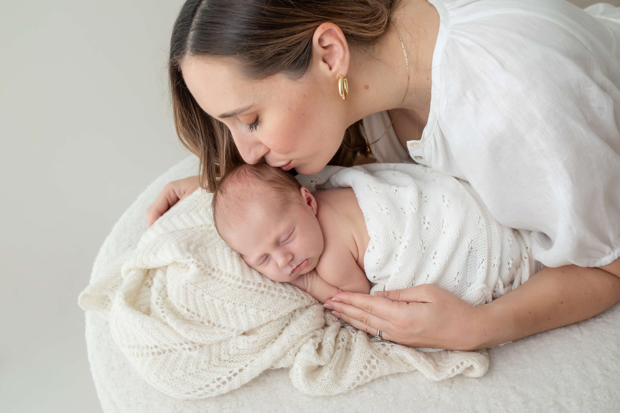 mum kissing newborn baby