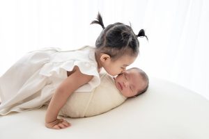 big sister kissing newborn baby